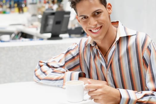 Portrait of a young man holding a cup of coffee and smiling