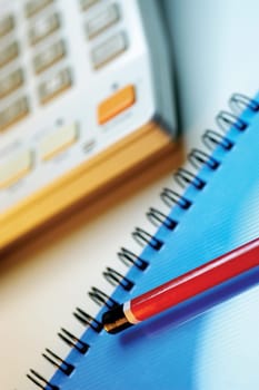 Calculator, red pencil and spiral bound notebook