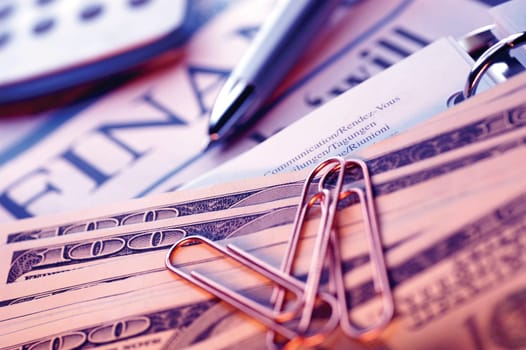 United States currency, pen, spiral notebook, planning list, financial section of newspaper and calculator, close-up