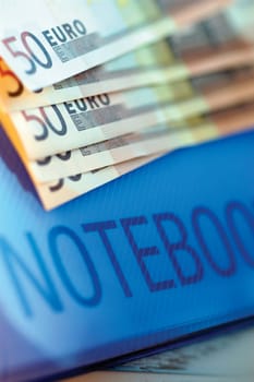 Close-up of five hundred Euro banknotes on a notebook