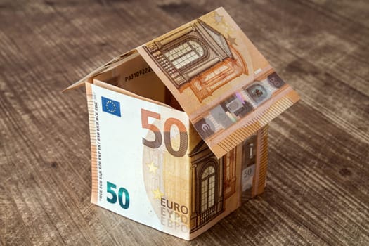 House made of fifty Euro banknotes on a wooden background