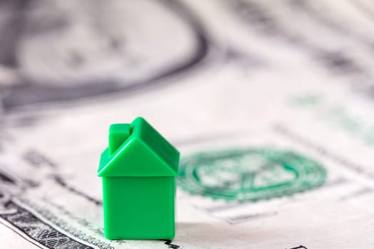 Miniature house on dollar banknote background. Concept for property ladder, mortgage and real estate investment