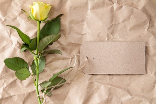 Single yellow rose with blank tag tied with string