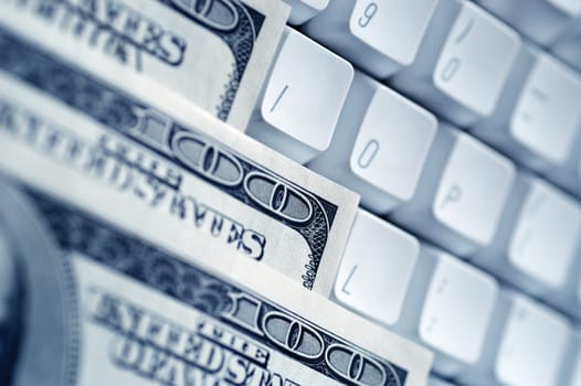 United States one hundred dollar bills on top of computer keyboard, close-up