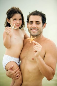 Portrait of a father and his daughter holding a starfish