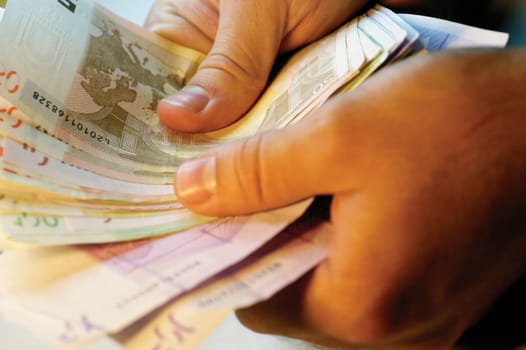 Man holding several Euro bank notes, close-up