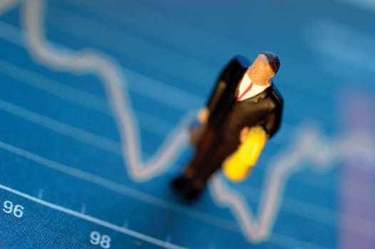 Toy businessman standing on top of graph