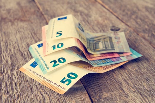 Close-up of Euro banknotes on wooden background. Filtered image.