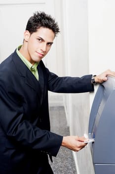 Portrait of a businessman inserting a credit card into an ATM