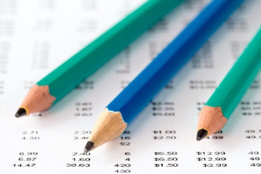 Macro view of three pencils on a report with many digits