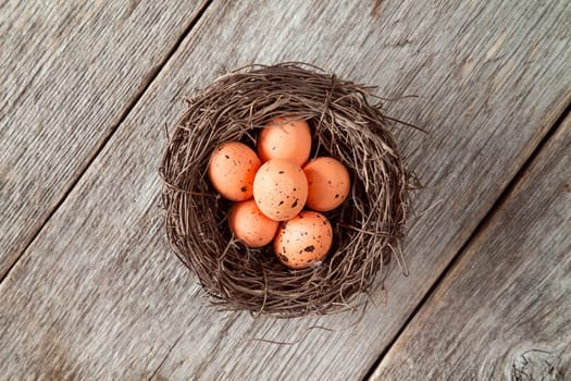 Nest with painted Easter eggs on wooden Background.Top view.