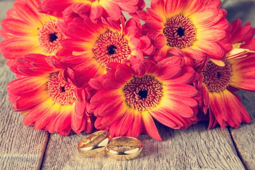 Two golden rings with beautiful gerberas on background