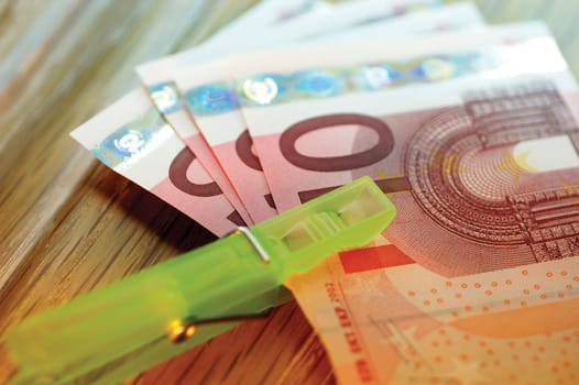 Close-up of a clothes peg on a stack of ten Euro banknotes