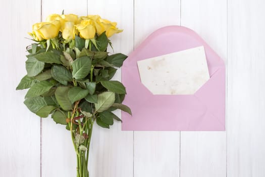 Yellow roses and love letter or note card with pink envelope