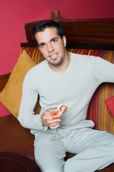 Portrait of a mid adult man sitting on a couch and holding a cocktail