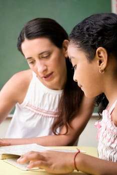 Female teacher teaching her student in a classroom