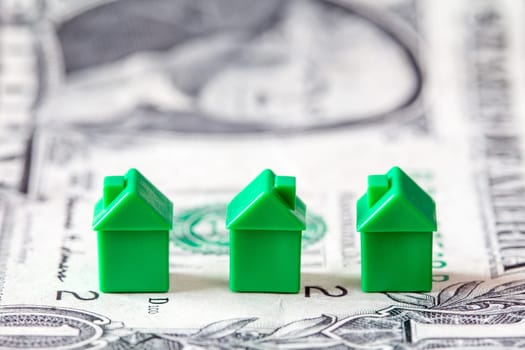Miniature houses on dollar banknote background. Concept for property ladder, mortgage and real estate investment