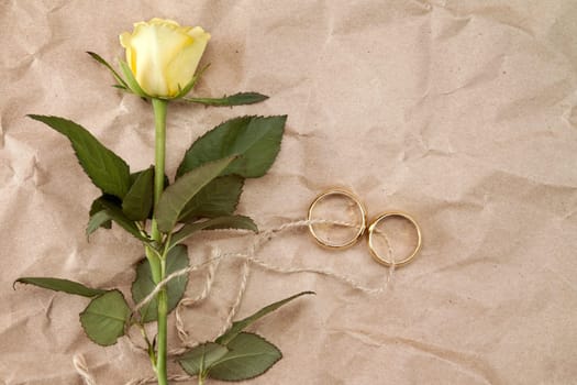 Two gold wedding rings and yellow roses tied with string