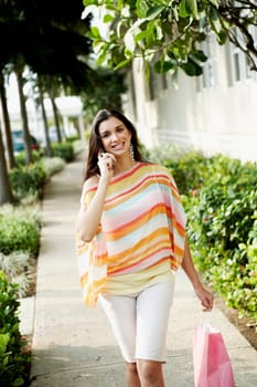 Portrait of a businesswoman carrying a shopping bag and talking on a mobile phone