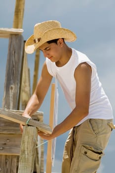 Side profile of a teenage boy building a wooden structure