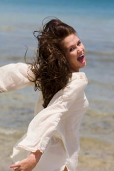 Portrait of a young woman on the beach with her arms outstretched