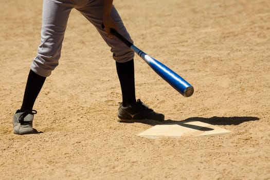 Low section view of a baseball player holding a baseball bat