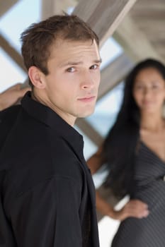 Portrait of a young man with a young woman in the background