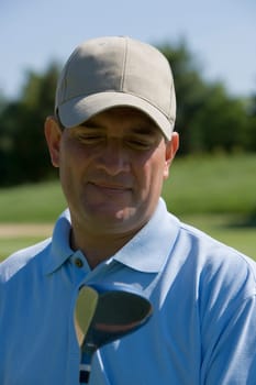 Close-up of a mature man with a golf club on a golf course