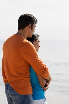 Side profile of a mid adult man embracing a young woman from behind