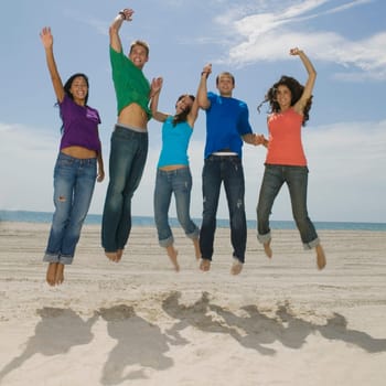 Portrait of five young people jumping on the beach