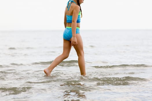 Side profile of a girl wading in water on the beach