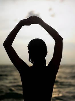 Silhouette of a young woman with her arms raised