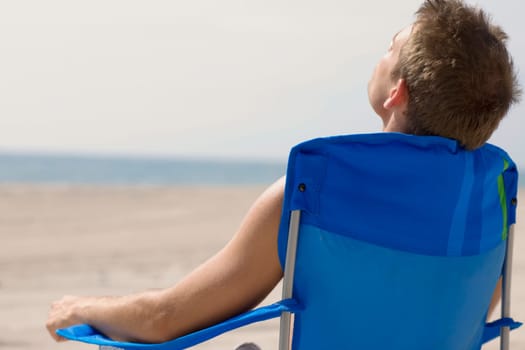 Rear view of a young man sitting on the beach