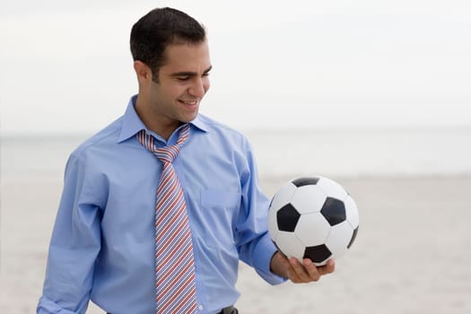 Close-up of a young man standing on the beach and holding a soccer ball