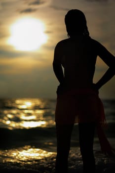 Silhouette of a young woman standing on the beach