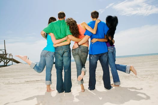 Rear view of five people standing on the beach