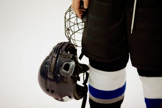 Mid section view of an ice hockey player holding a helmet