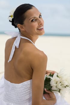 Portrait of a young woman smiling and holding flowers on the beach