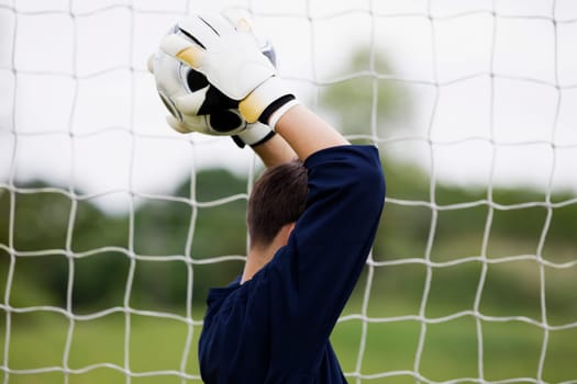 Side profile of a goalie holding a soccer ball over his head