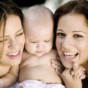 Close-up of two young women holding a baby girl