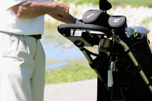 Mid section view of a man putting a golf club into a golf bag