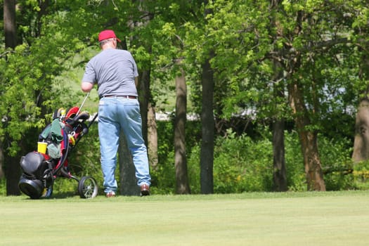 Rear view of a man pulling a golf bag on a trolley