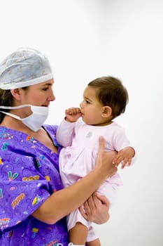 Side profile of a female doctor holding a baby girl sucking her thumb