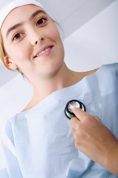 Close-up of a doctorŽs hand holding a stethoscope and examining a female patient