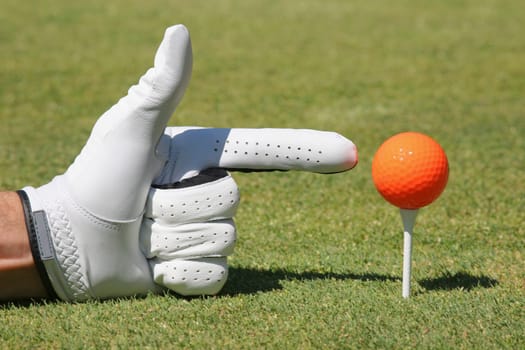 Close-up of a personŽs hand pointing at a golf ball on a golf tee