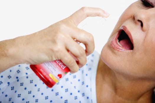 Close-up of a senior woman spraying mouthwash into her mouth