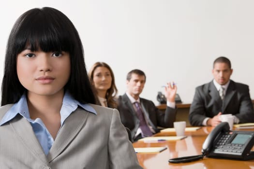 Portrait of a businesswoman smiling with other business executives in a board room