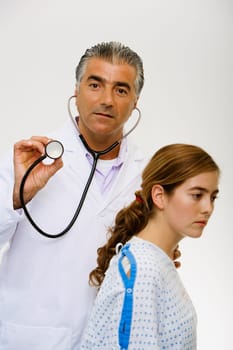 Portrait of a male doctor standing beside a young woman and holding a stethoscope