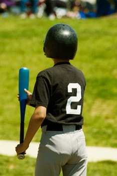 Rear view of a baseball player holding a baseball bat