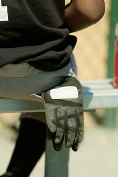 Mid section view of a baseball player sitting on a bench